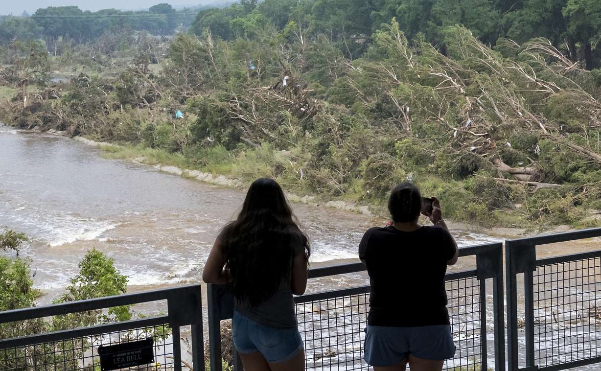 Onlookers review the damage along the Guadalupe River caused by recent flooding, Sunday, in Kerrville, Texas.