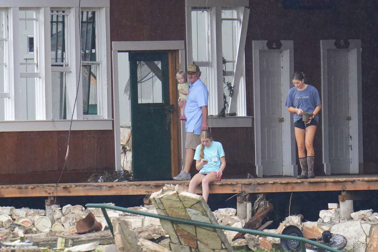 A person salvages a bell from the main building at Camp Mystic along the banks of the Guadalupe River after a flash flood swept through the area Sunday in Hunt, Texas.