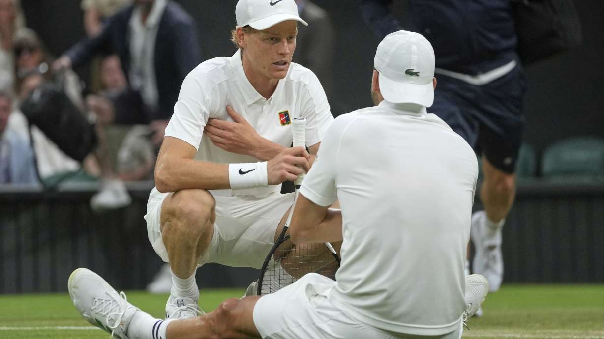 Italy's Jannik Sinner checks on Bulgaria's Grigor Dimitrov after he went down with an injury during a fourth round men's singles match at the Wimbledon Tennis Championships in London, Monday, July 7, 2025.