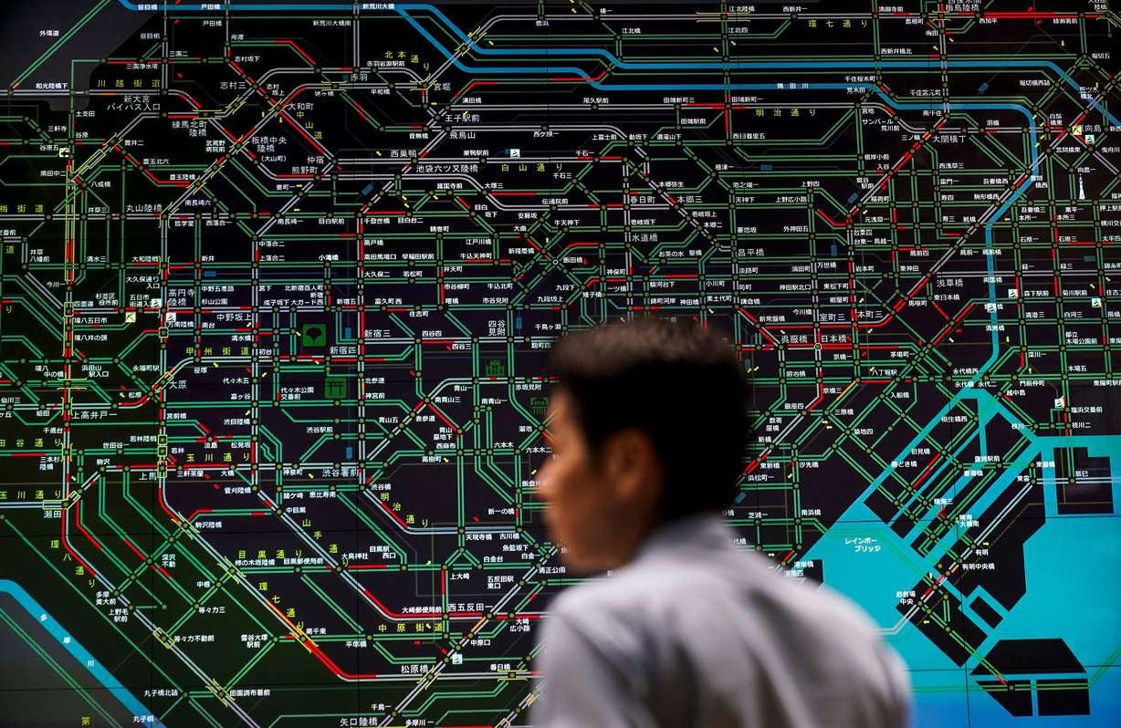 In this July 26, 2019, photo, an officer monitors the flow of public transportation in front of a screen showing Tokyo's web of train lines at the Tokyo Metropolitan Police Department's traffic control center in Tokyo. Tokyo has one of the most advanced public transport systems in the world, but before the city hosted the 2020 Olympic Games, local governments, companies and commuters were bracing for unprecedented strain the events could put on rail transit and highways.