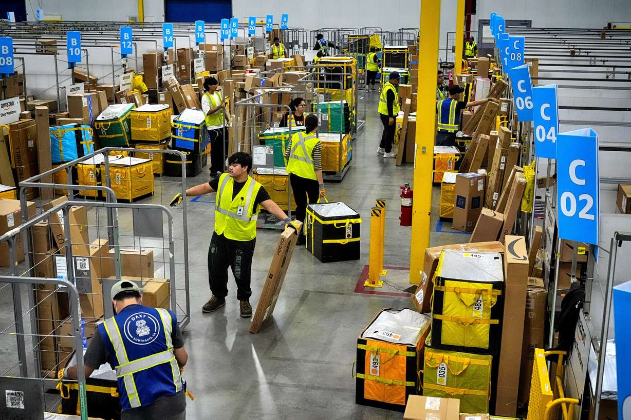 Amazon employees load packages on carts before being put on to trucks for distribution for Amazon's annual Prime Day event at an Amazon's DAX7 delivery station, July 16, 2024, in South Gate, Calif.