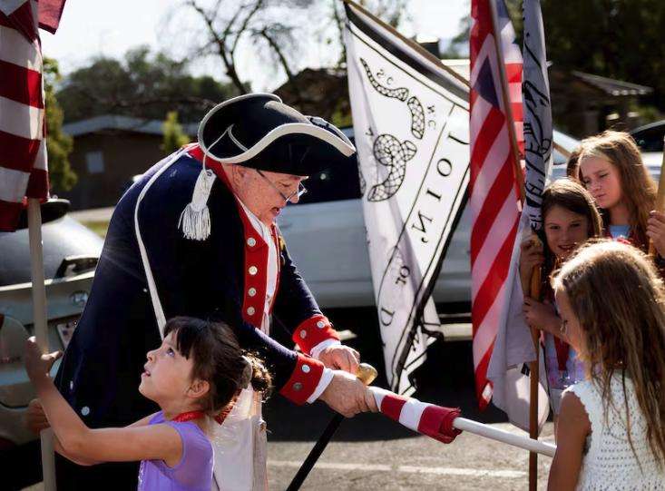 Doug McGregor, a member of the Utah Society Sons of the American Revolution, helps Liberty's Light Day Camp For Young Patriots campers unfurl flags in Murray City Park on June 27.