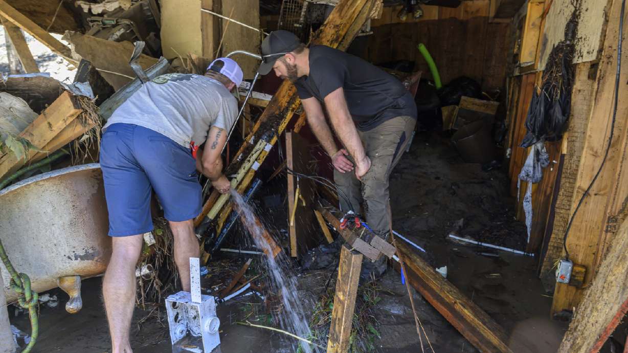 Wes Schenki and Neal Clawson work to shut off exposed water pipes in a cabin along the Rio Ruidoso Wednesday morning, in Ruidoso, N.M. The village is preparing for another round of rain after flooding killed three people.