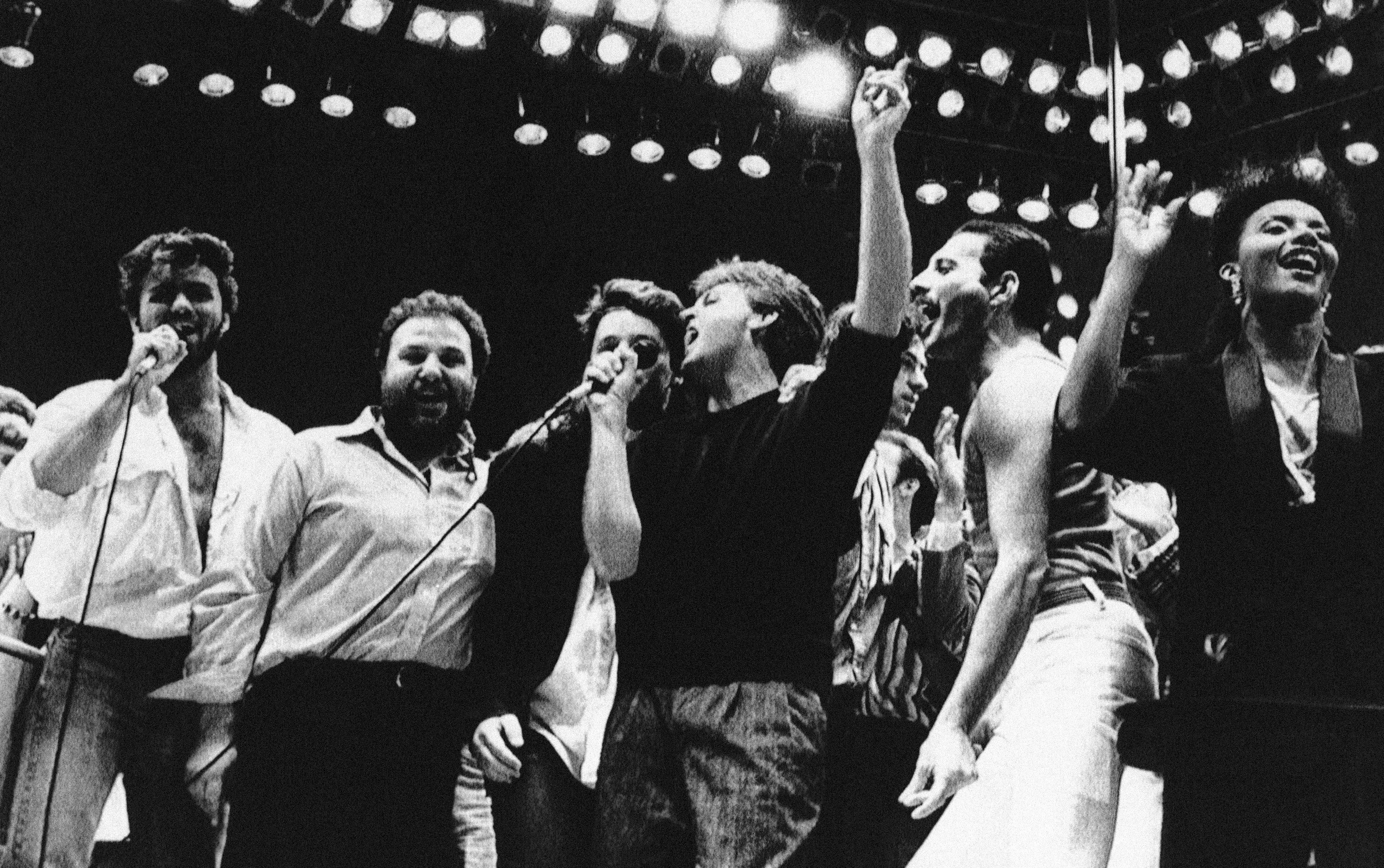 George Michael, from left, concert promoter Harvey Goldsmith, Bono, Paul McCartney, Bob Geldof, and Freddie Mercury appear during the London Live Aid Famine Relief Concert in London on July 13, 1985.