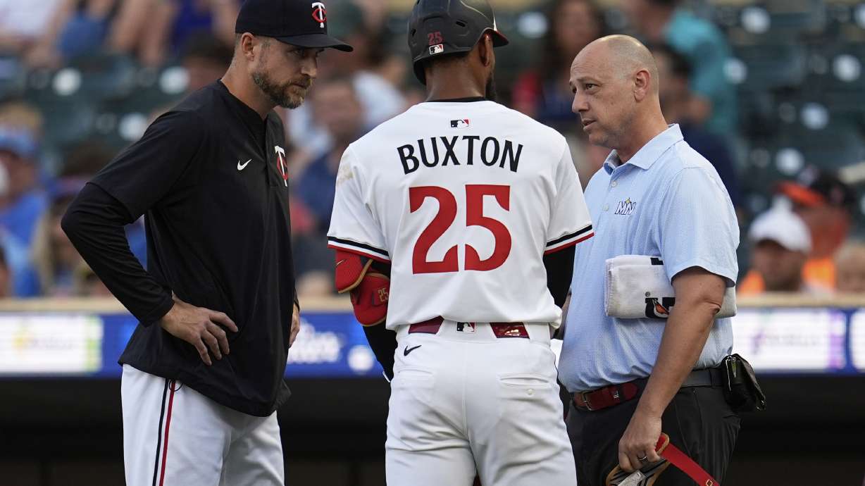 Minnesota Twins' Byron Buxton (25) is looked at by manager Rocco Baldelli (5), left, and a trainer after being hit by a pitch during the first inning of a baseball game against the Chicago Cubs Wednesday, July 9, 2025, in Minneapolis.