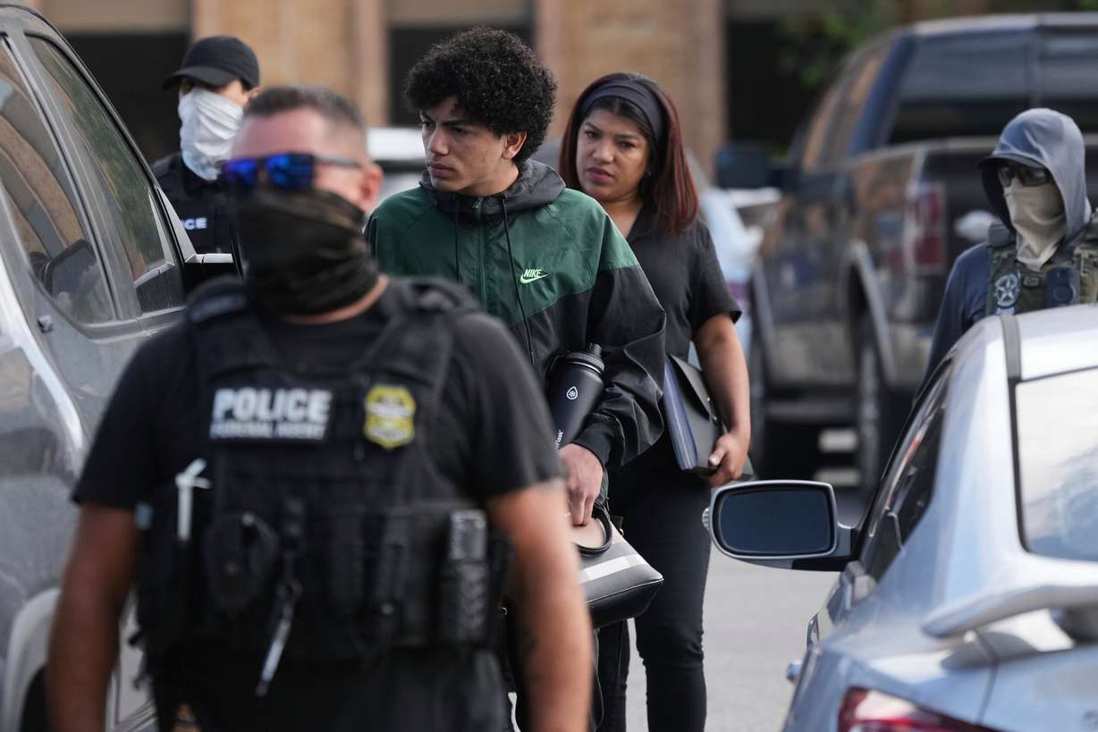 A man and woman are detained and escorted to a bus by federal agents following an appearance at immigration court, June 23, in San Antonio. The number of arrested unauthorized immigrants have tripled since President Trump's second term began.