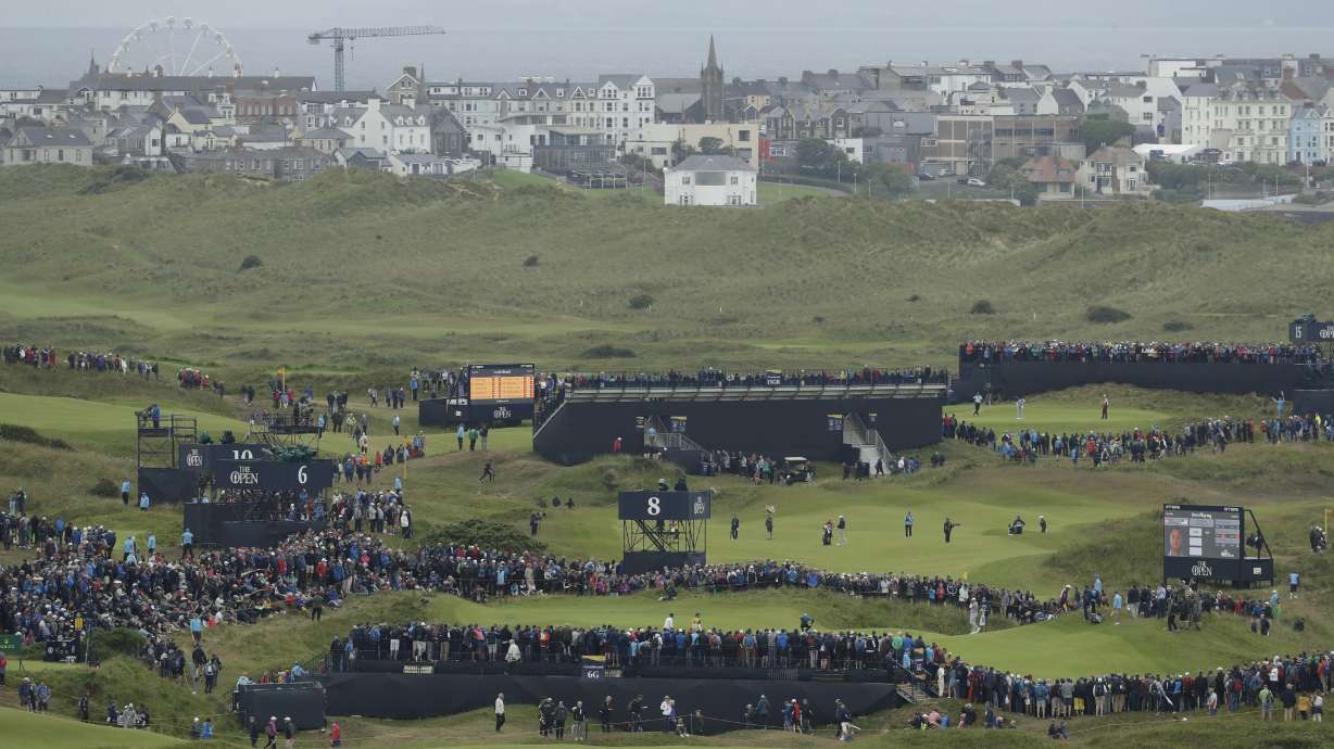 FILE - Northern Ireland's Rory McIlroy, in blue top and cap, squats down to look at his putt on the 6th green during the first round of the British Open Golf Championships at Royal Portrush in Northern Ireland, July 18, 2019.