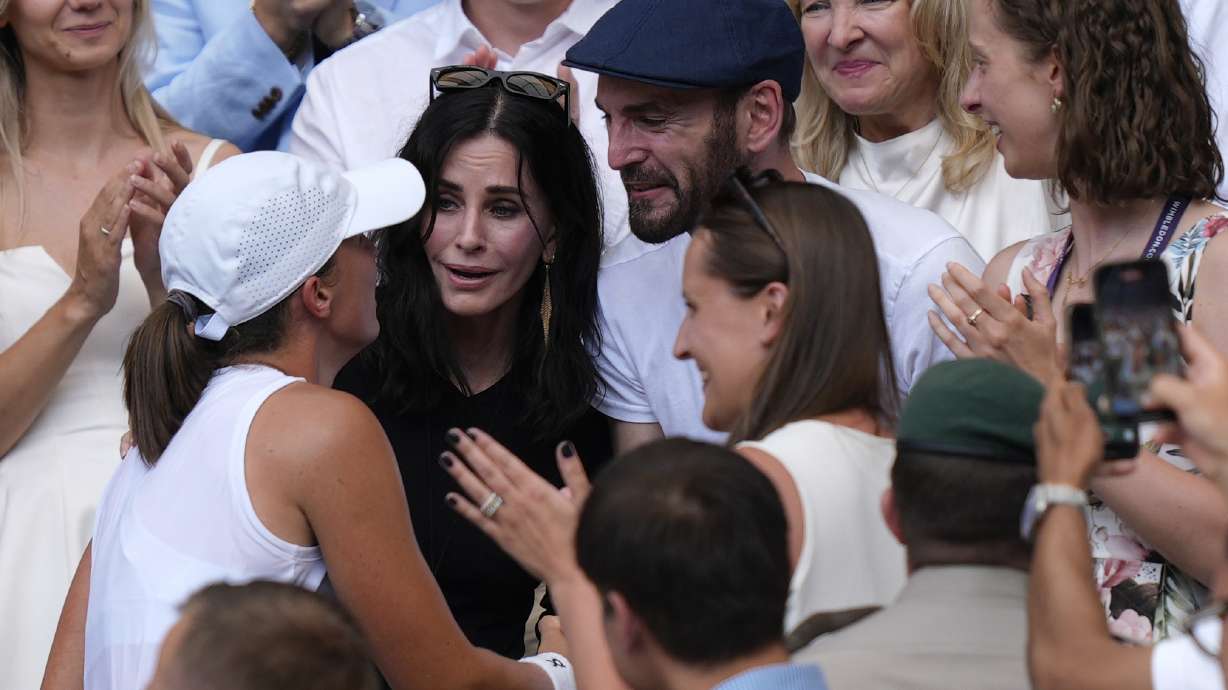Courteney Cox, center, and Johnny McDaid celebrate with Poland’s Iga Swiatek as she greets her coaches, friends and family after beating Amanda Anisimova of the U.S. to win the women’s singles final at the Wimbledon Tennis Championships in London, Saturday, July 12, 2025.