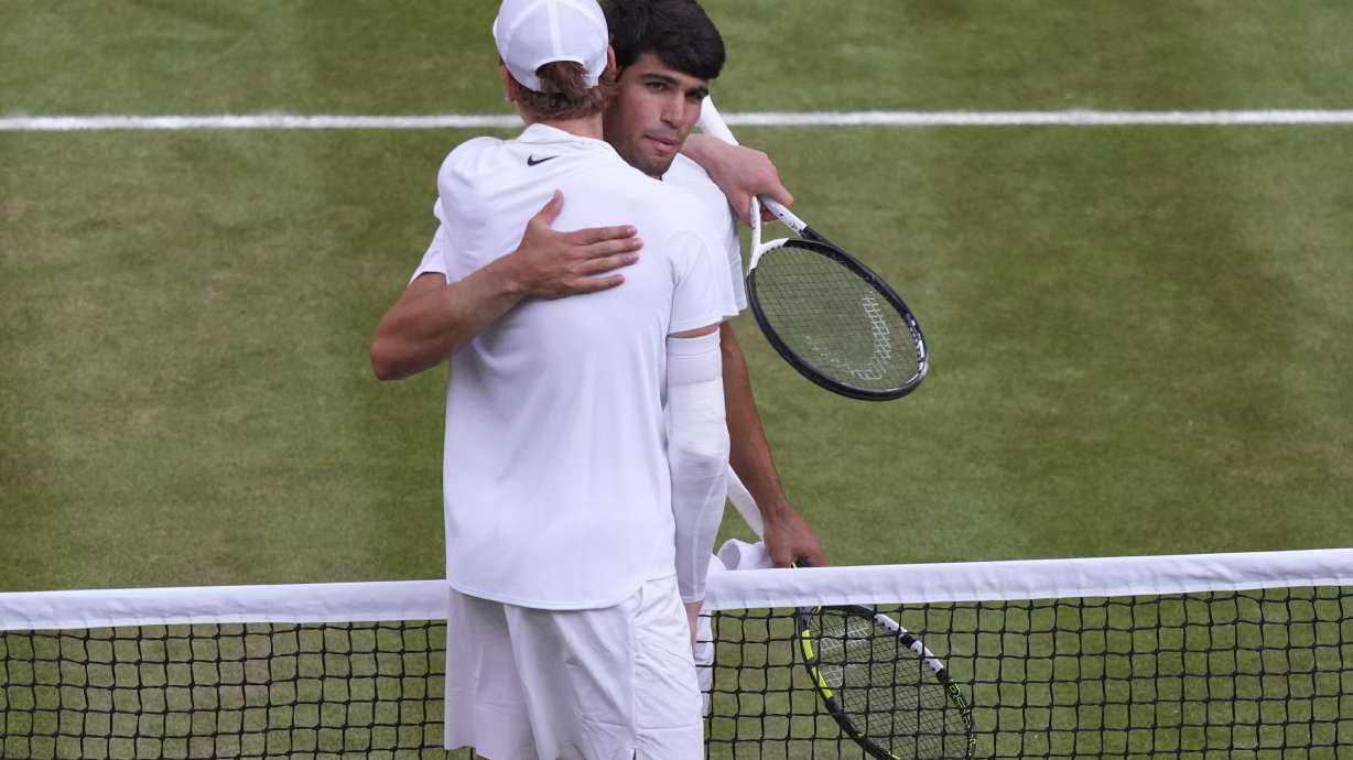 Italy's Jannik Sinner, left, greets Carlos Alcaraz of Spain at the net after beating him to win the men's singles final at the Wimbledon Tennis Championships in London, Sunday, July 13, 2025.