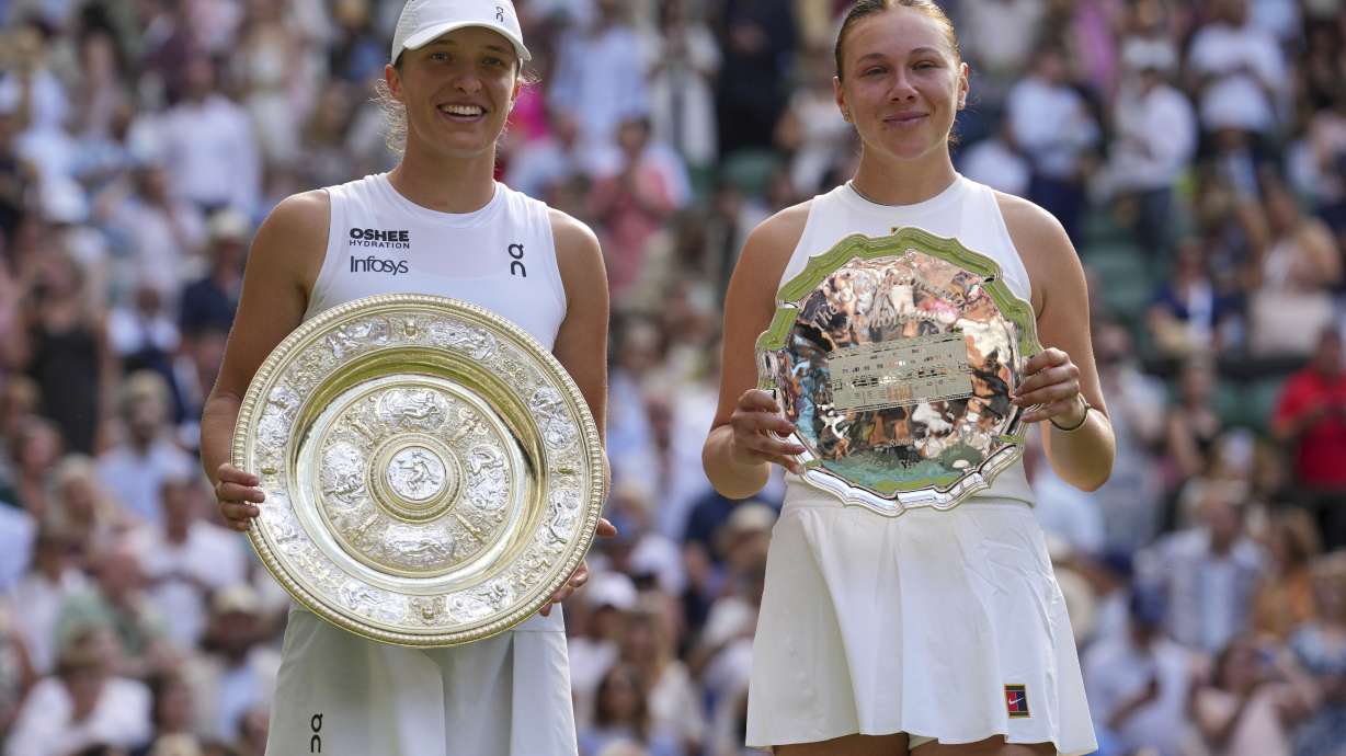 Poland's Iga Swiatek, left, celebrates with the trophy after beating Amanda Anisimova of the U.S., right, to win the women's singles final at the Wimbledon Tennis Championships in London, Saturday, July 12, 2025.