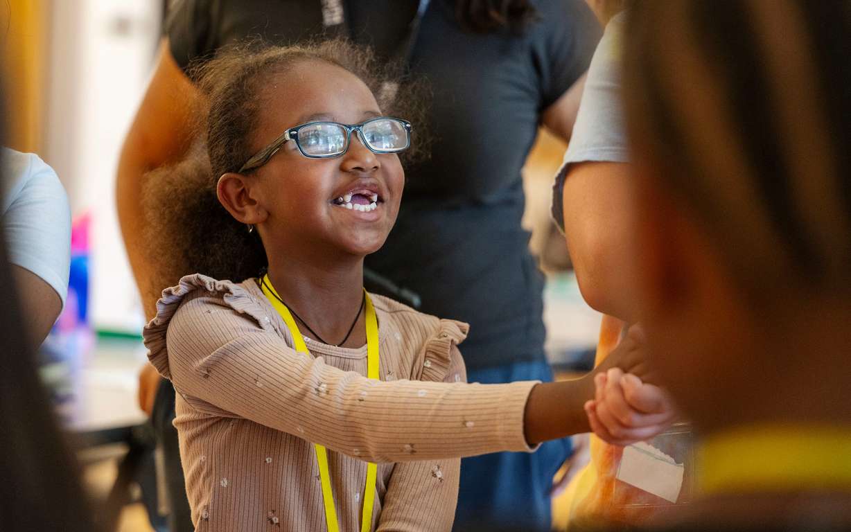 Selihom smiles as she and other girls circle up at the end of their Girl Scouts class as they take part in summer activities assisted by counselors at Central Park Community Center in South Salt Lake City on Monday.
