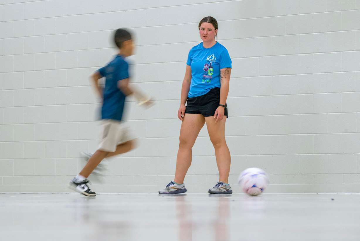 Deborah, a counselor, helps one of the kids in soccer practice during summer activities at Central Park Community Center in South Salt Lake City on Monday.