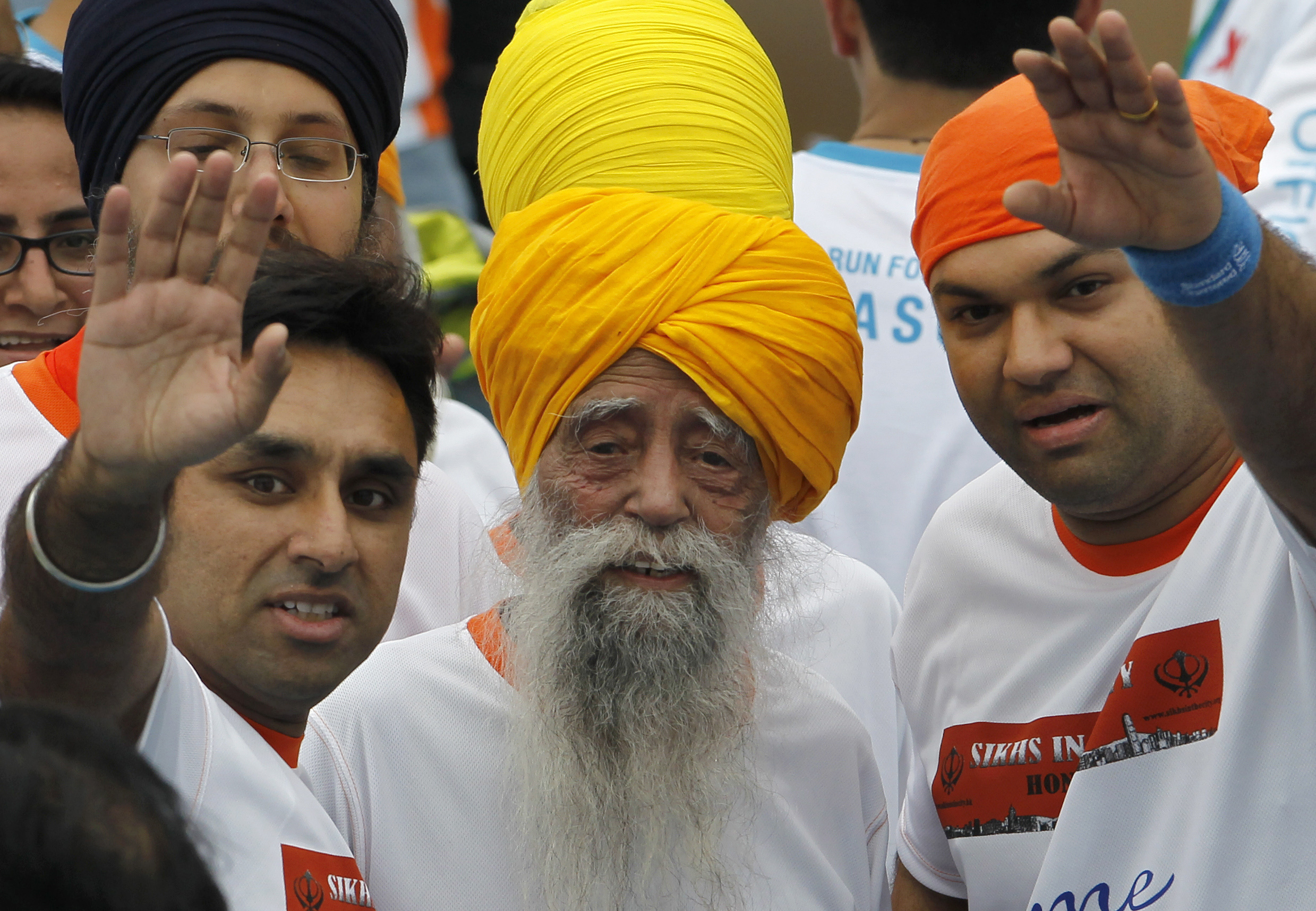 FILE - Centenarian marathon runner Fauja Singh, center, smiles after finishing a 10-kilometer race, held as part of the annual Hong Kong Marathon, in Hong Kong, Feb. 24, 2013.