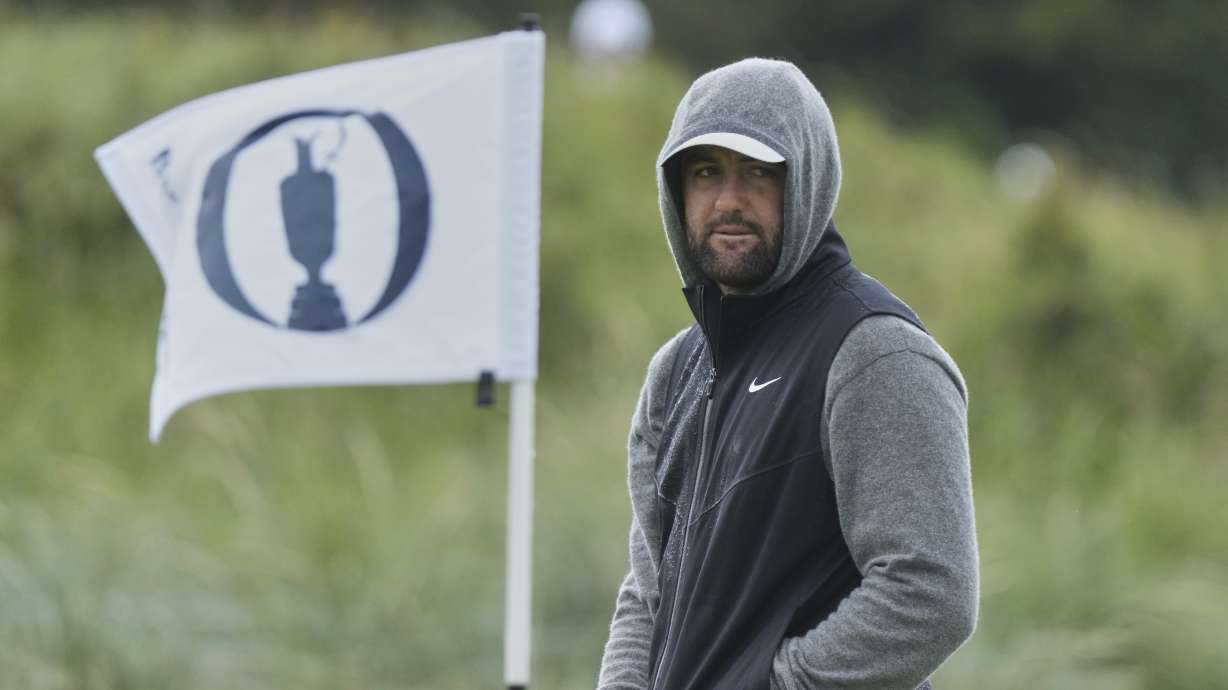 Scottie Scheffler of the United States keeps warm after putting on the 9th green during a practice round for the British Open golf championship at the Royal Portrush Golf Club, Northern Ireland, Tuesday, July 15, 2025.