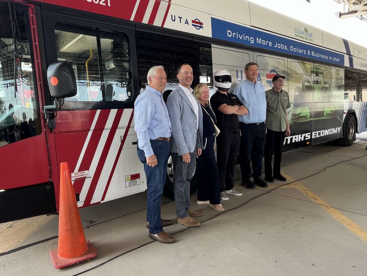 Utah Transit Authority and Wasatch Front Regional Council leaders pose for a photo in front of a bus with an ad touting UTA's economic benefits during an event in Salt Lake City on Wednesday.