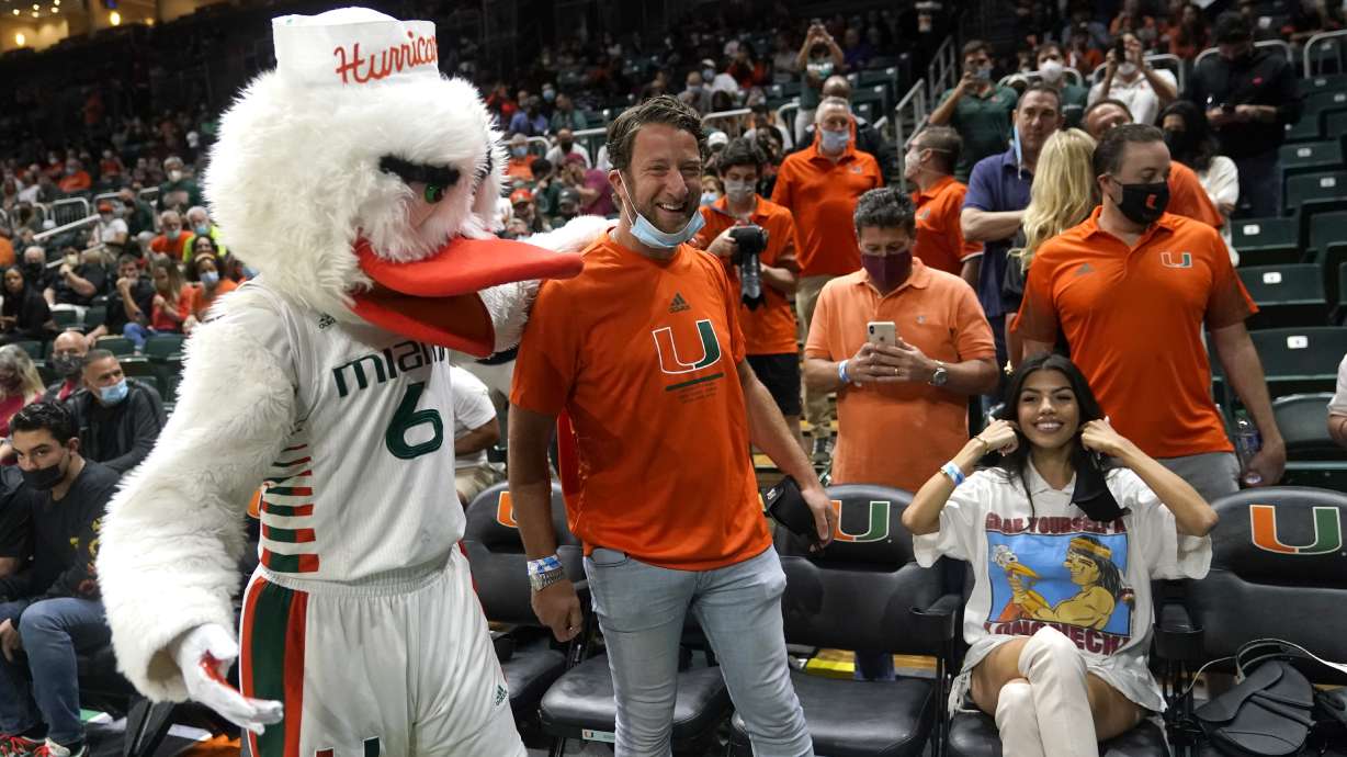 Barstool Sports blogger David Portnoy, center, poses with the Miami mascot Sebastian the Ibis during the first half of an NCAA college basketball game against Florida State, Jan. 22, 2022, in Coral Gables, Fla.