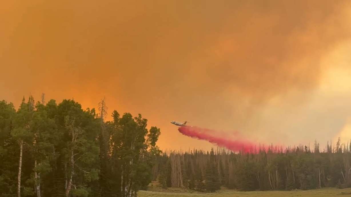 A plane dumps fire retardant onto the Monroe Canyon Fire in Sevier County on Tuesday. At least three cabins have now been destroyed by the fire, authorities said Thursday.