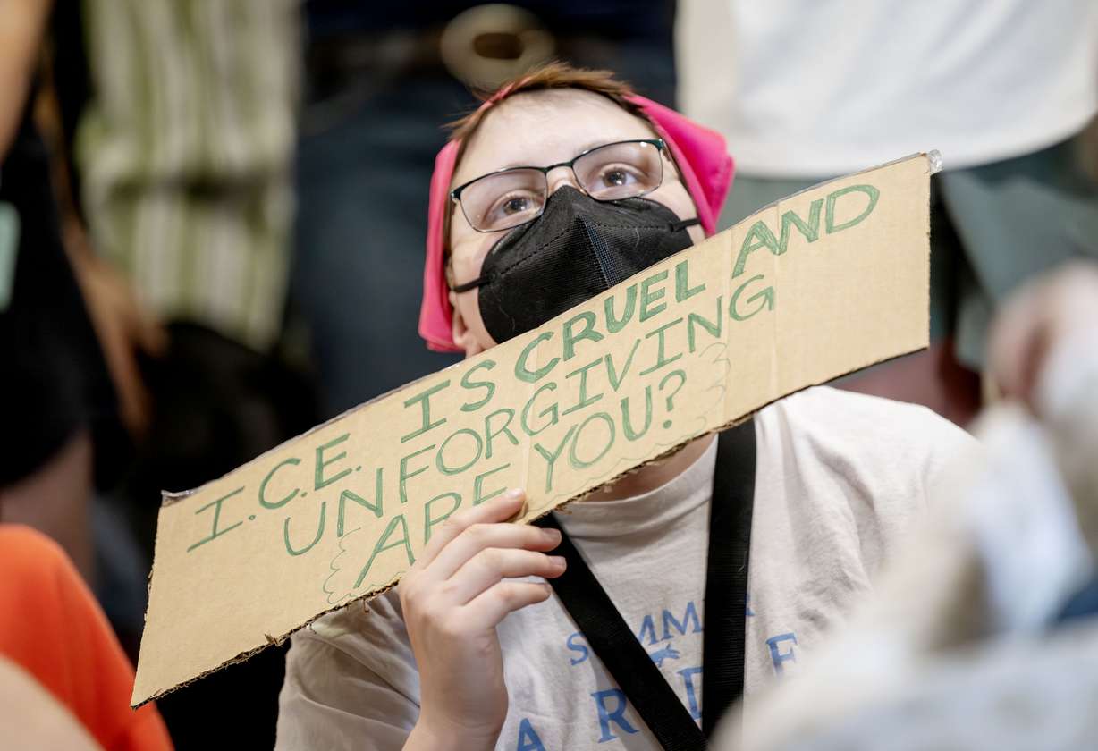 Hans Armstrong holds a sign at a Utah County Commission meeting on planned cooperation between the Utah County Sheriff's Office and ICE in Provo on Wednesday.