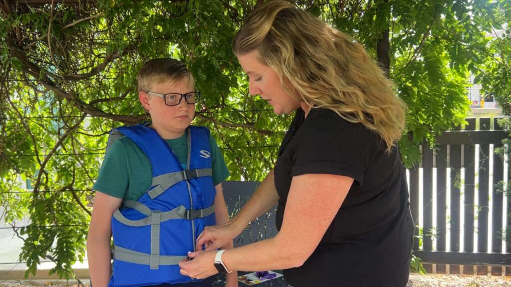 Michelle Jamison with Intermountain Health demonstrates how to properly fit a life jacket, Thursday. Jamison said wearing a life jacket is always a good idea, even for experienced swimmers.
