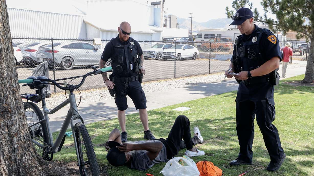 Salt Lake police officers Joe Paxman and Kade Palmer inform a man that camping on park strips is illegal in Salt Lake City on Wednesday. Gov. Spencer Cox said Thursday he's pleased with the progress the city has made with its public safety plan.