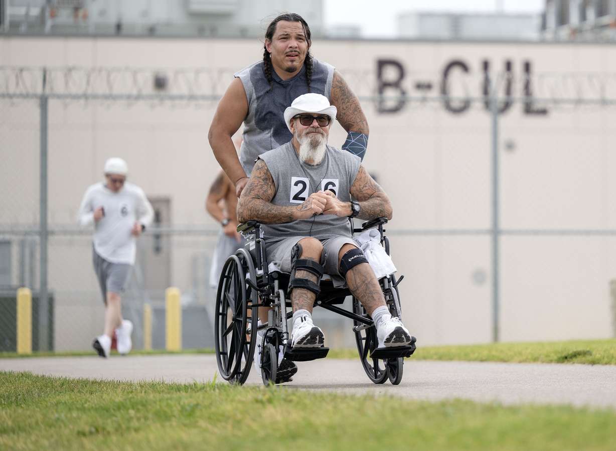 Jaime Salinas pushes Howard Nelson in a wheelchair as they and other inmates at the Utah State Correctional Facility in Salt Lake City participate in a half marathon at the facility on Friday.