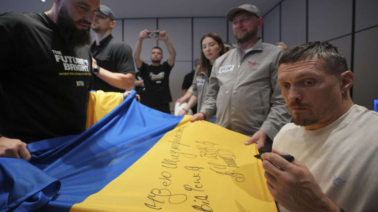 Ukraine's boxer Oleksandr Usyk signs autograph as he meets the Ukrainian war veterans, who are employees of Ukrainian power company DTEK at a hotel in Battersea Park in London, Thursday, July 17, 2025 ahead of the undisputed heavyweight champion boxing fight between Britain's Daniel Dubois and Oleksandr Usyk on Saturday.