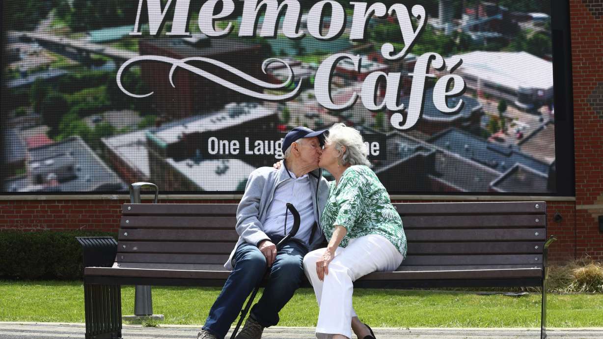 Mario and Gail Cirasunda, of Orchard Park, N.Y., share a kiss on a bench following a Memory Cafe event at the National Comedy Center May 5, in Jamestown, N.Y.
