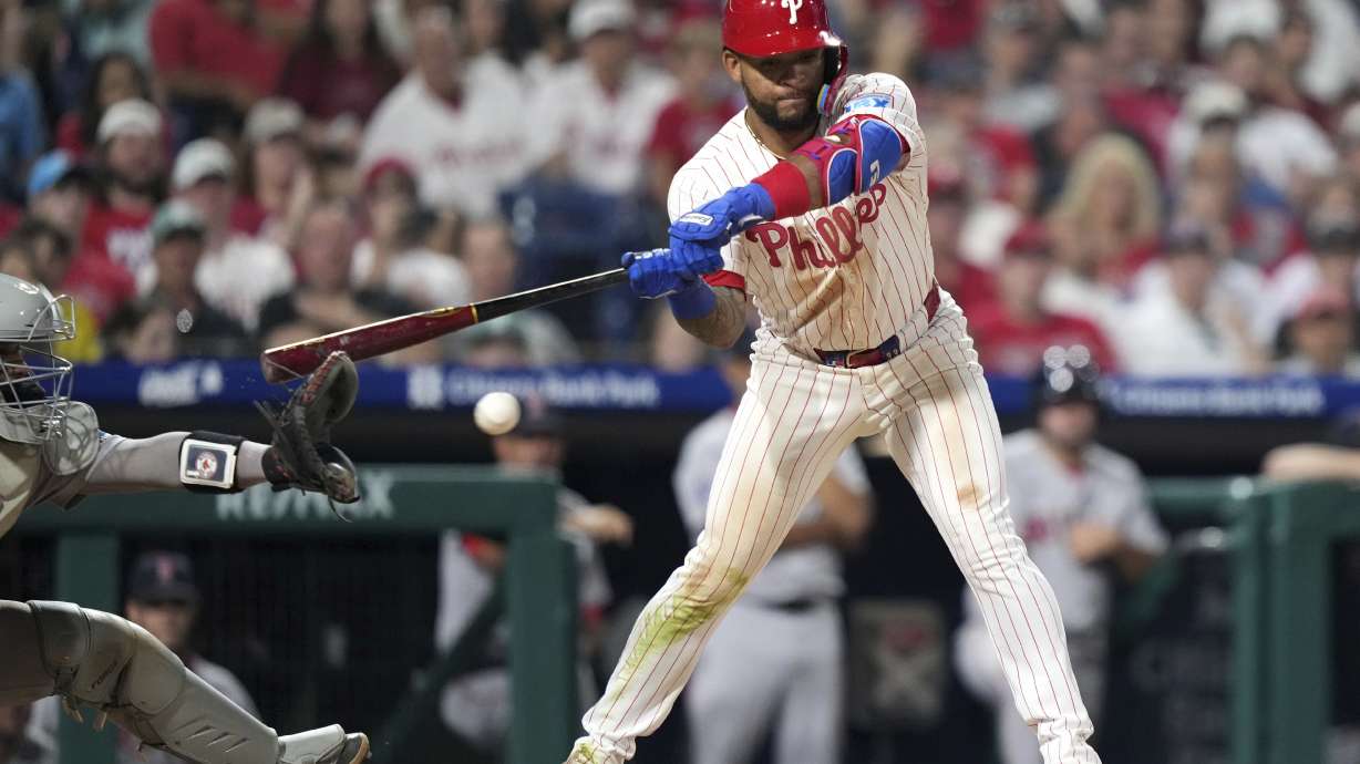 Philadelphia Phillies' Edmundo Sosa, right, hits the glove of Boston Red Sox catcher Carlos Narváez for catcher's interference with the bases loaded in the 10th inning of a baseball game Monday, July 21, 2025, in Philadelphia.