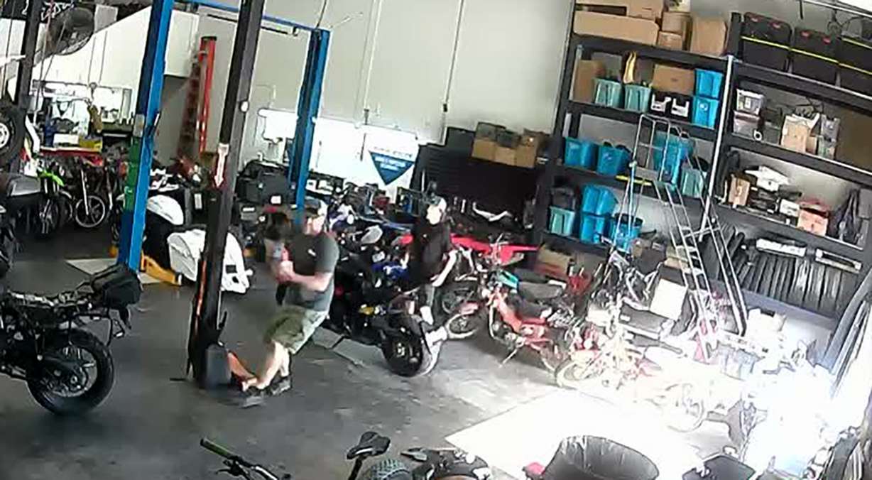 A security camera shows an employee of Fastback Moto in Woods Cross grabbing an extinguisher after a fire and explosion at a neighboring storage facility on Monday. Officials credit the Fastback employees for their quick action.