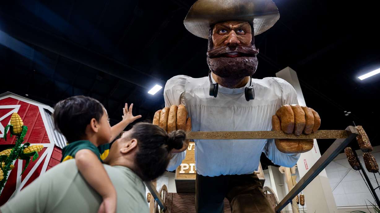 Anapesi Brown holds her son, Amanaki Brown, 2, as he looks up at the Herriman Mirabella Stake float during the Days of ’47 2025 Float Preview Party at the Mountain America Exposition Center in Sandy on Tuesday.
