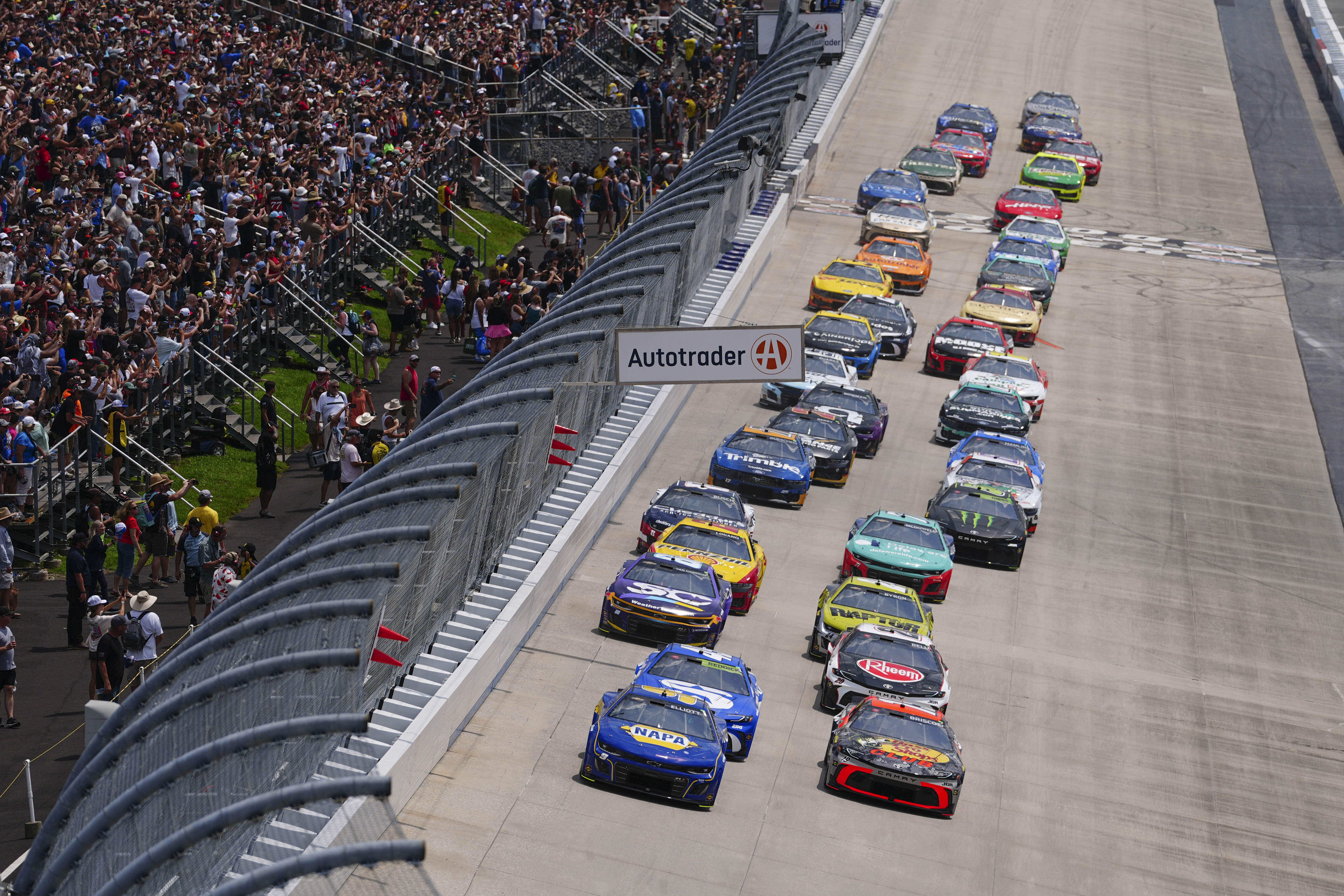 Chase Elliott (9) and Chase Briscoe (19) lead the field down the front stretch during a NASCAR Cup Series auto race at Dover Motor Speedway, Sunday, July 20, 2025, in Dover, Del.