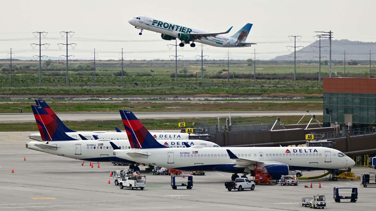 A Frontier Airlines airliner lifts off at Salt Lake City International Airport while Delta Air Lines planes sit at their gates in Salt Lake City on May 4, 2024.