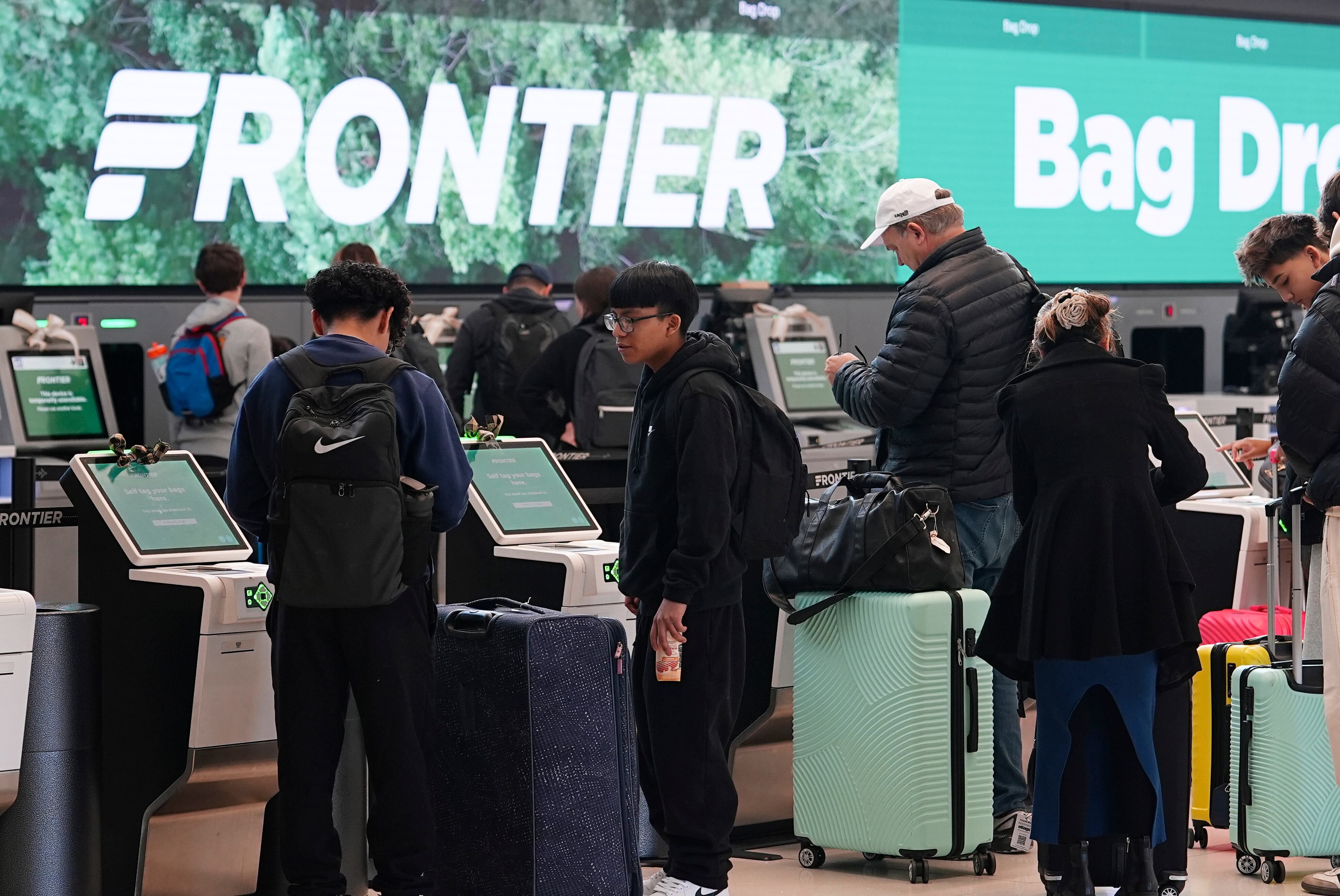 Travellers line up at the Frontier Airlines self-check kiosks in Denver International Airport, Dec. 24, 2024, in Denver. Frontier Airlines recently announced 15 new routes, including a direct flight from Salt Lake City International Airport to John Wayne Airport in Santa Ana, Calif.