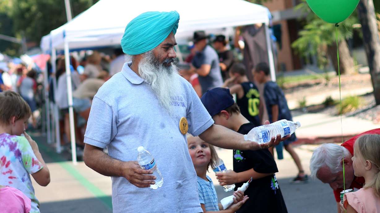 Surinder Singh hands out bottles of water to attendees of the Days of '47 Parade in Salt Lake City on July 24, 2024. Utah may not feel the heat like much of the country will this week, but people still need to pay attention for signs of heat illnesses.