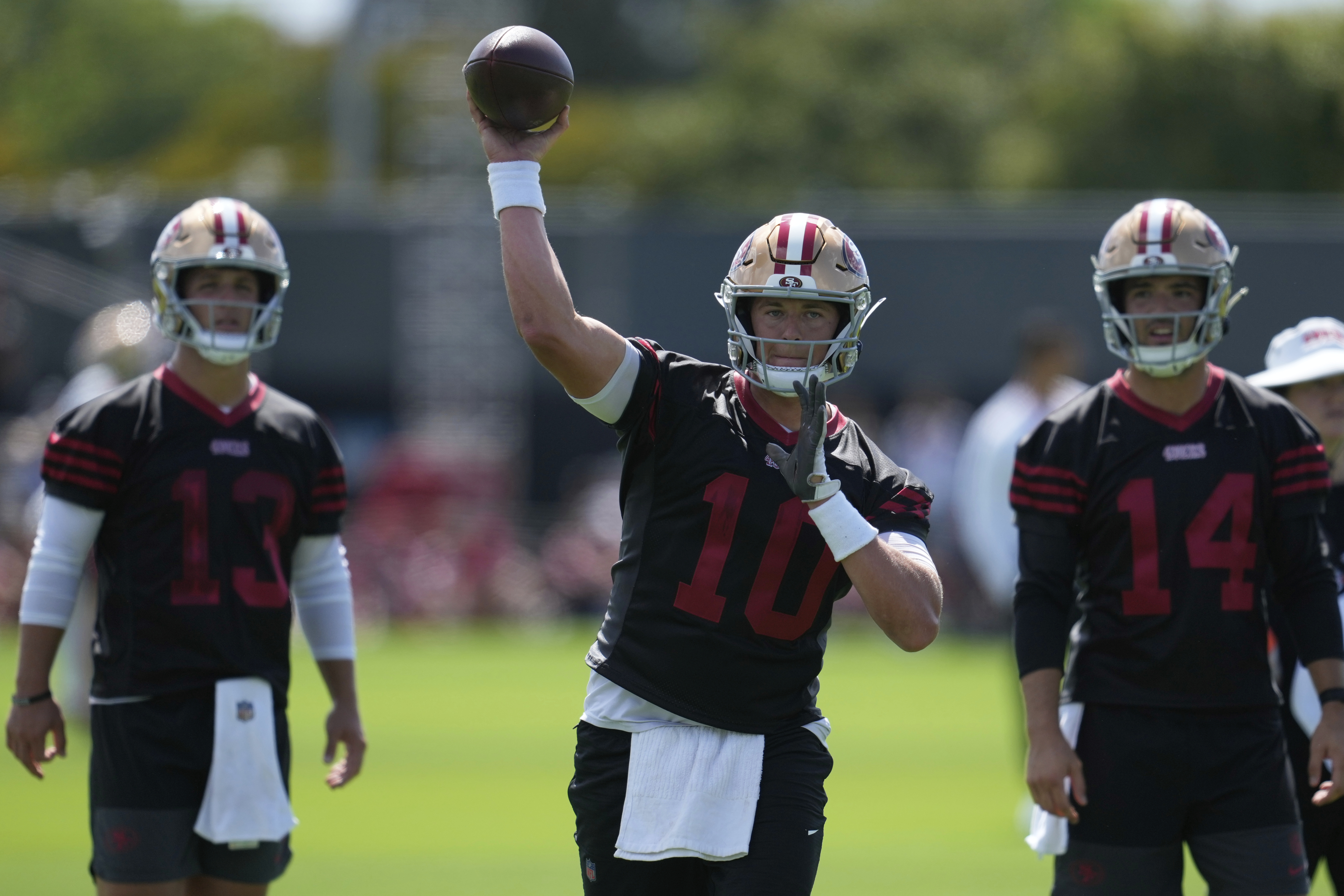 San Francisco 49ers quarterback Mac Jones (10) throws a pass between quarterbacks Brock Purdy (13) and Tanner Mordecai (14) during practice at the team's NFL football training camp, Wednesday, July 23, 2025, in Santa Clara, Calif. 