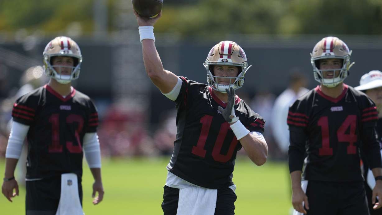 San Francisco 49ers quarterback Mac Jones (10) throws a pass between quarterbacks Brock Purdy (13) and Tanner Mordecai (14) during practice at the team's NFL football training camp, Wednesday, July 23, 2025, in Santa Clara, Calif.