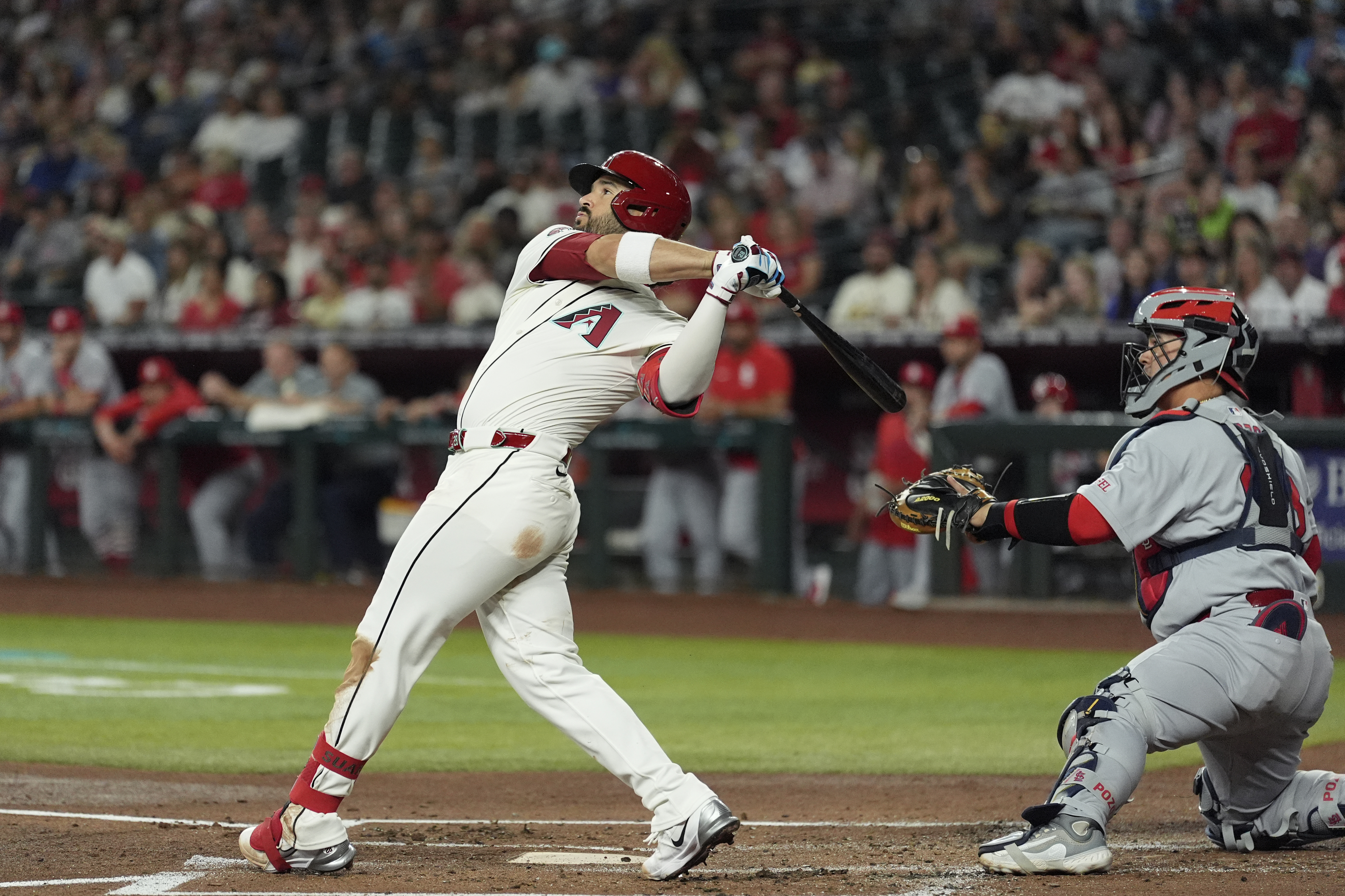 Arizona Diamondbacks' Eugenio Suárez, left, watches the flight of his three-run home run as St. Louis Cardinals catcher Yohel Pozo, right, looks on during the first inning of a baseball game Sunday, July 20, 2025, in Phoenix. 