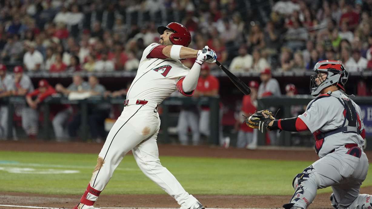 Arizona Diamondbacks' Eugenio Suárez, left, watches the flight of his three-run home run as St. Louis Cardinals catcher Yohel Pozo, right, looks on during the first inning of a baseball game Sunday, July 20, 2025, in Phoenix.