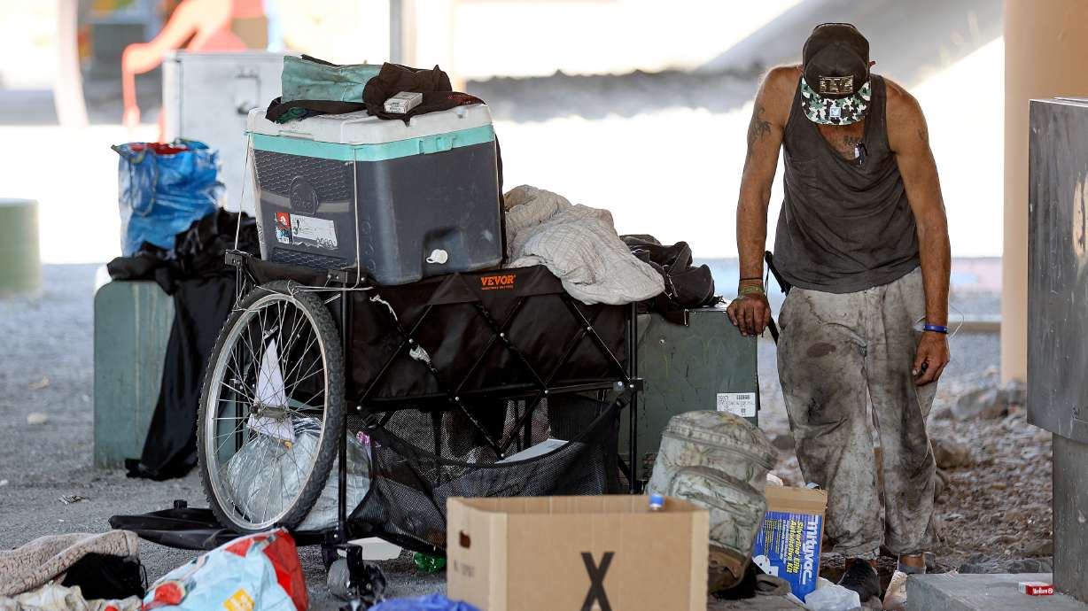 A man experiencing homelessness pauses while organizing his belongings under an overpass in Salt Lake City on Friday.