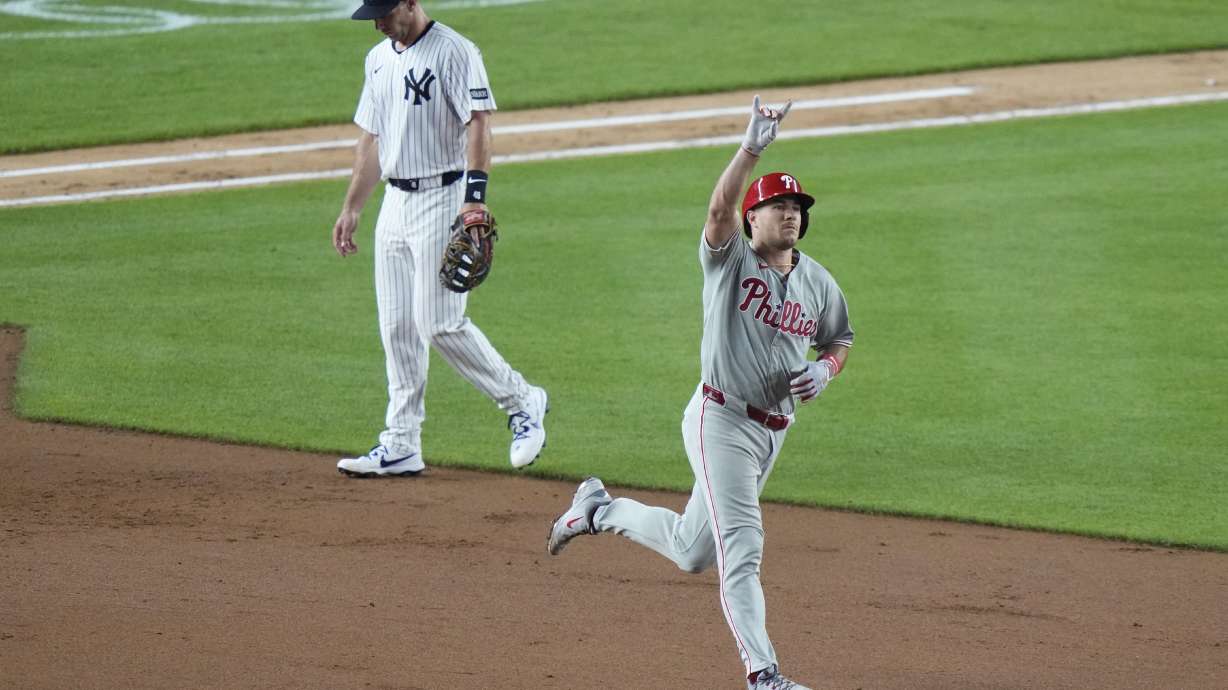 Philadelphia Phillies' J.T. Realmuto, right, runs past New York Yankees Paul Goldschmidt as he runs the bases after hitting a three-run home run during the seventh inning of a baseball game Friday, July 25, 2025, in New York.