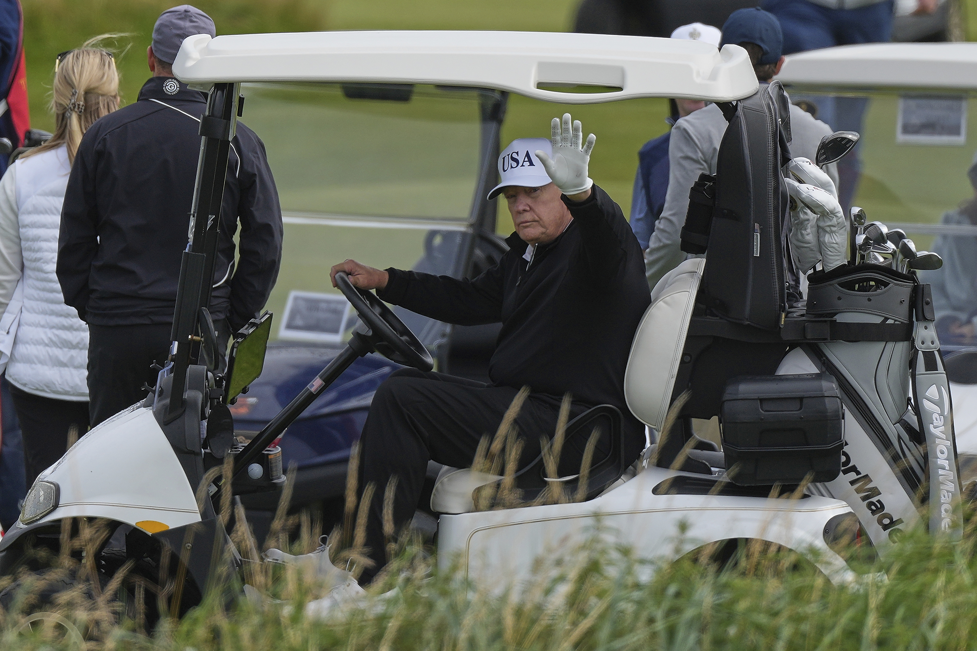 President Donald Trump waves to reporters as he sits in his golf cart at the Trump Turnberry golf course in Turnberry, Scotland, Saturday, July 26, 2025.