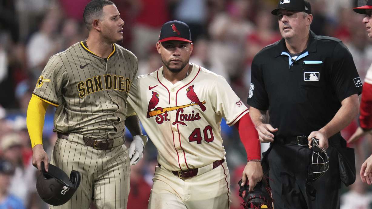 San Diego Padres' Manny Machado, left, is held back by St. Louis Cardinals' Willson Contreras (40) after being hit by a pitch as home plate umpire Lance Barrett, right, watches during the ninth inning of a baseball game against the St. Louis Cardinals Saturday, July 26, 2025, in St. Louis.