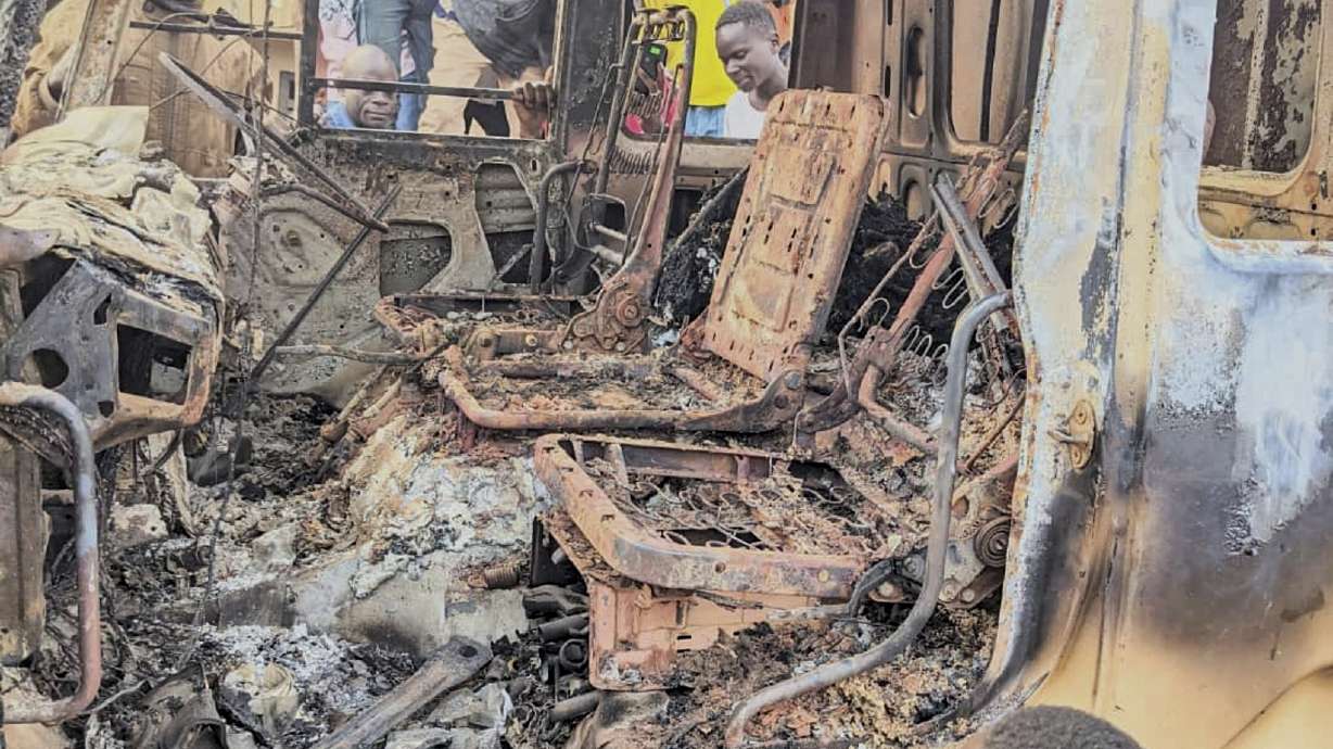 People gather around the charred remains of a burned vehicle following a deadly attack in Komanda, Ituri province of eastern Congo, Sunday.