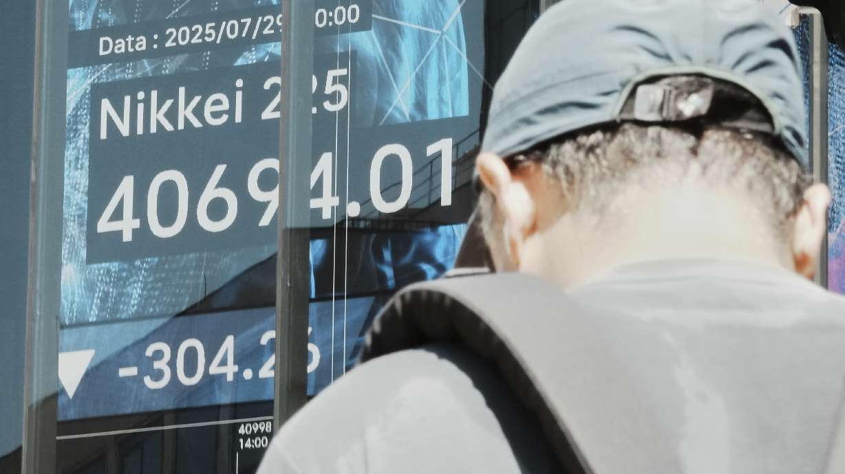 A person stands in front of an electronic stock board showing Japan's Nikkei index at a securities firm Tuesday, in Tokyo. U.S. stock indexes are edging back from their record levels as a busy week for Wall Street picks up momentum.