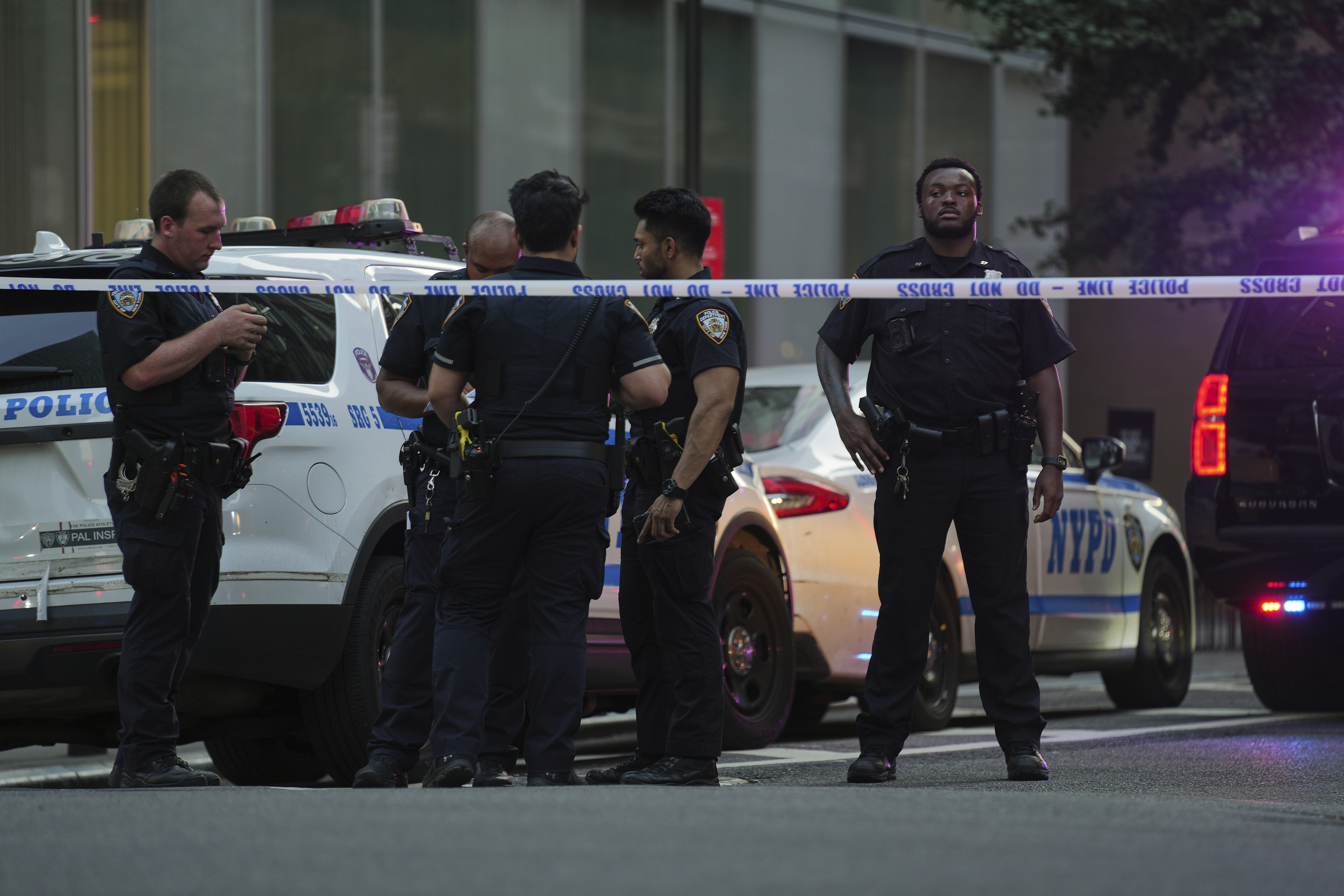 A New York Police officers gather at the scene on 52nd Street outside a Manhattan office building where two people were shot, including a New York police officer, Monday, July 28, 2025, in New York. 