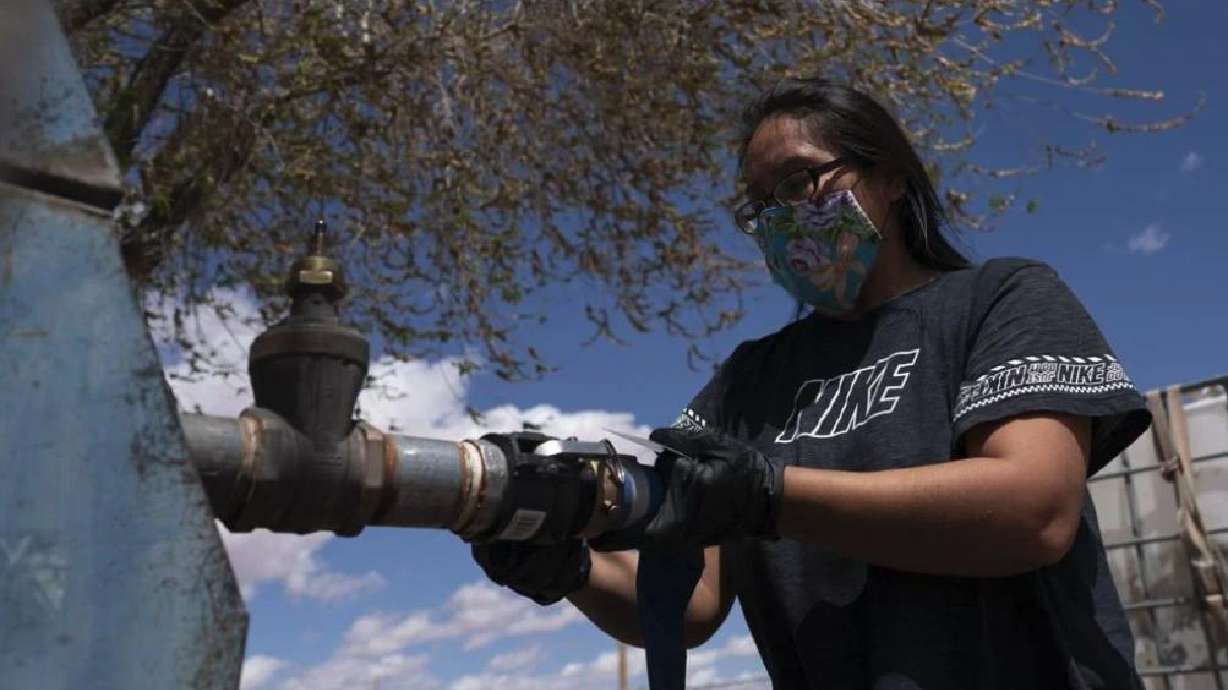 Raynelle Hoskie attaches a hose to a water pump to fill tanks in her truck outside a tribal office on the Navajo reservation in Tuba City, Ariz., on April 20, 2020. The Navajo Nation is working to secure water rights settlements in Arizona.