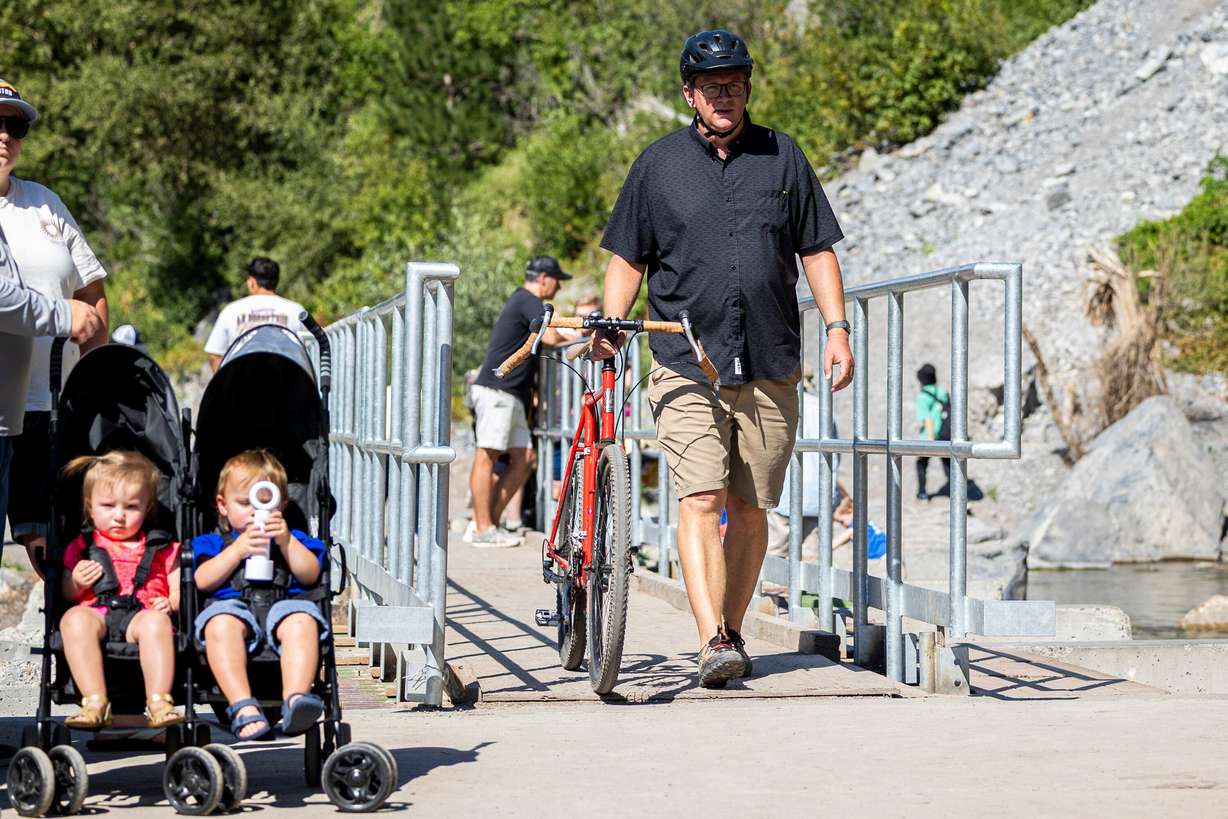 Brad Huber, of Orem, walks his bike across the bridge at the base of the falls at Bridal Veil Falls in Provo Canyon, July 19.