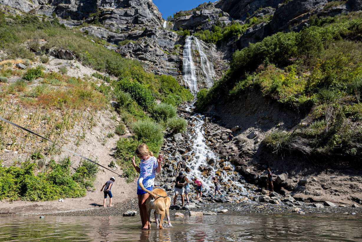 Roselyn Grill, 6, of Orem, stands on a rock with her mother’s dog, Timon, as they play at the base of the falls at Bridal Veil Falls in Provo Canyon, July 19.