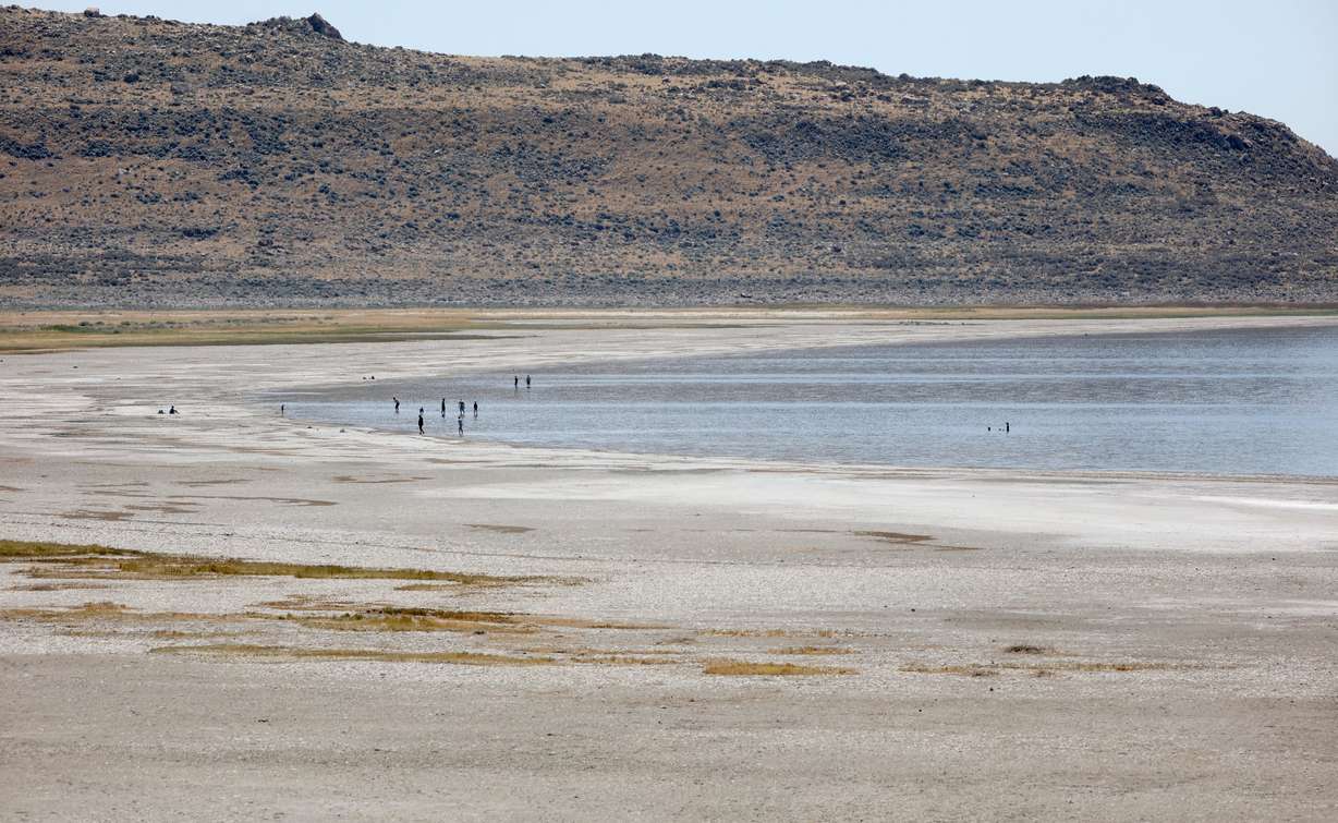 People wade in the waters of the Great Salt Lake on Antelope Island on July 29. Gov. Spencer Cox recently announced a goal to raise the lake to 4,198 feet by the 2034 Winter Olympics.