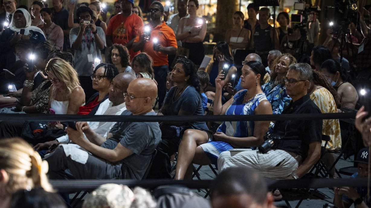 People raise their phone lights during the vigil for the victims killed in the previous day's shooting at 345 Park Avenue, including NYPD officer Didarul Islam, in Bryant Park, Tuesday, July 29, 2025, in New York.
